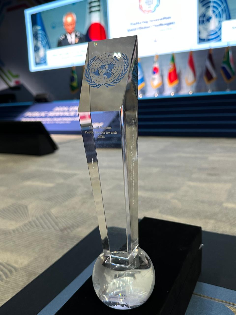 Prêmio recebido pela ONU. Ele tem um formato vertical, é de vidro e possui o logotipo da ONU.